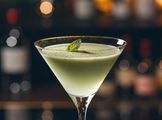 Elegant pale-jade matcha martini dusted with matcha and a mint leaf