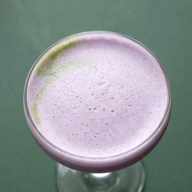 Ube matcha shakerato in a coupe with a lilac foam cap